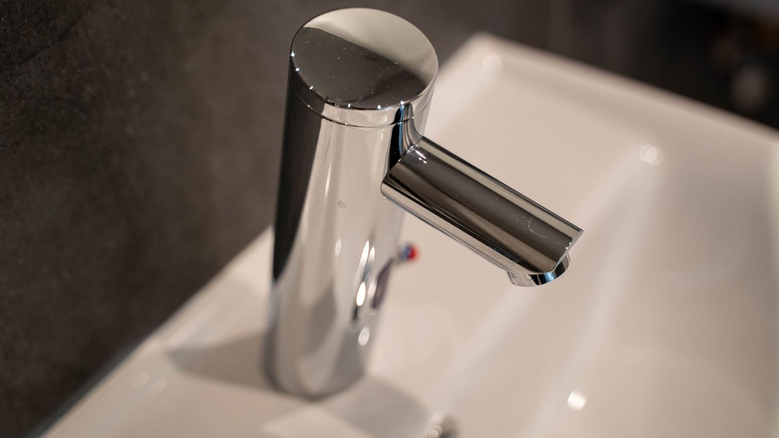 Mitigeur chromé de lavabo photographié en gros plan sur vasque blanche