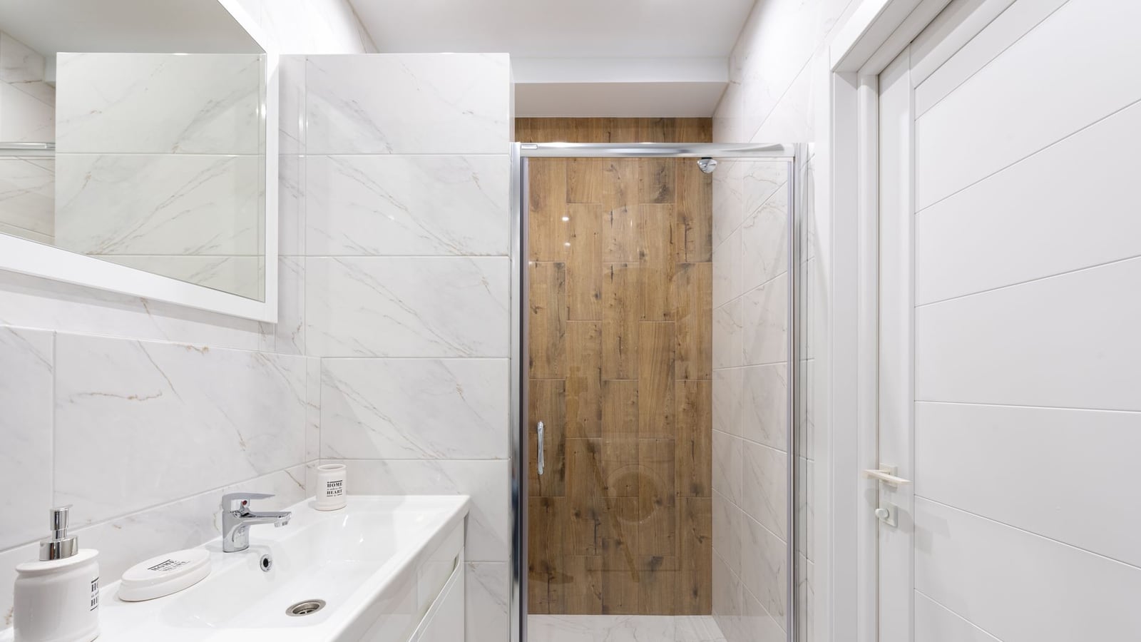 Salle de bains lumineuse en marbre blanc avec douche en bois