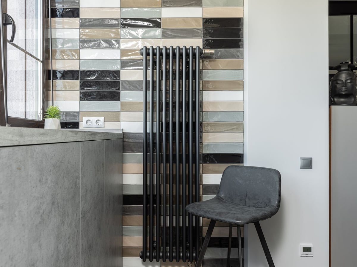 Radiateur vertical anthracite posé dans une pièce carrelée