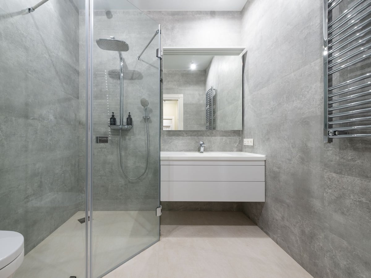 Salle de bains rénovée avec douche vitrée et meuble vasque blanc